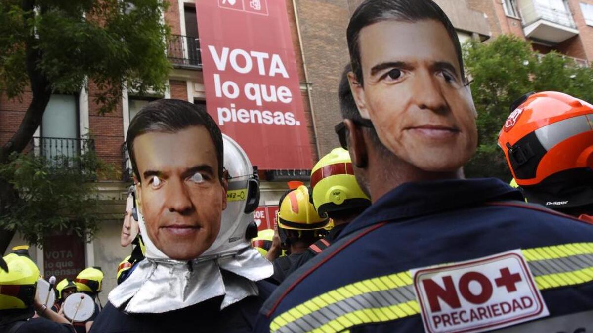 Protesters with their backs turned with Pedro Sanchez's mask at the headquarters of the Spanish socialist worker party during the demonstration. Firefighters have come out to protest in the streets of Madrid against the working conditions imposed on them by the Spanish government. (Photo by Richard Zubelzu / SOPA Images/Sipa USA)