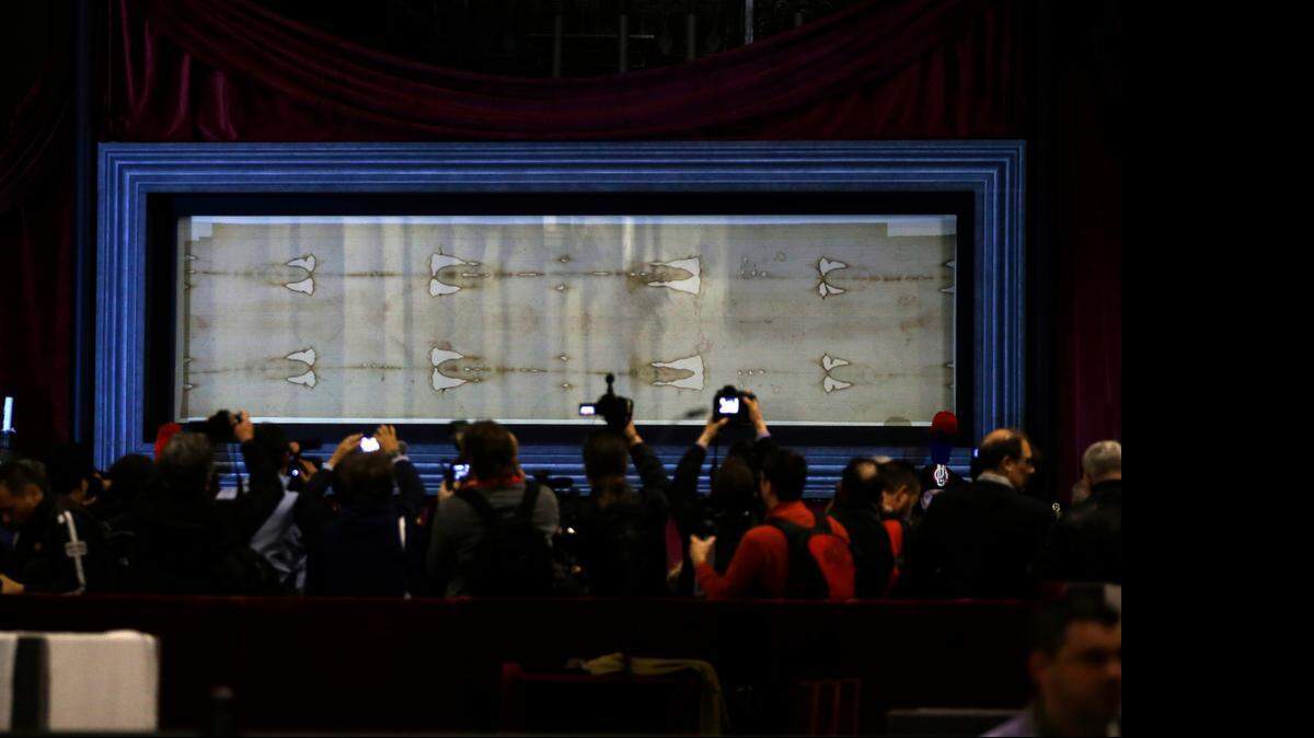 <cutline_leadin>El Santo</cutline_leadin> Sudario durante una presentación a la prensa, el sábado, en la Catedral de Turín, Italia, y será expuesto al público a partir del domingo, donde un millón de personas ya han reservado su entrada.<252><252>