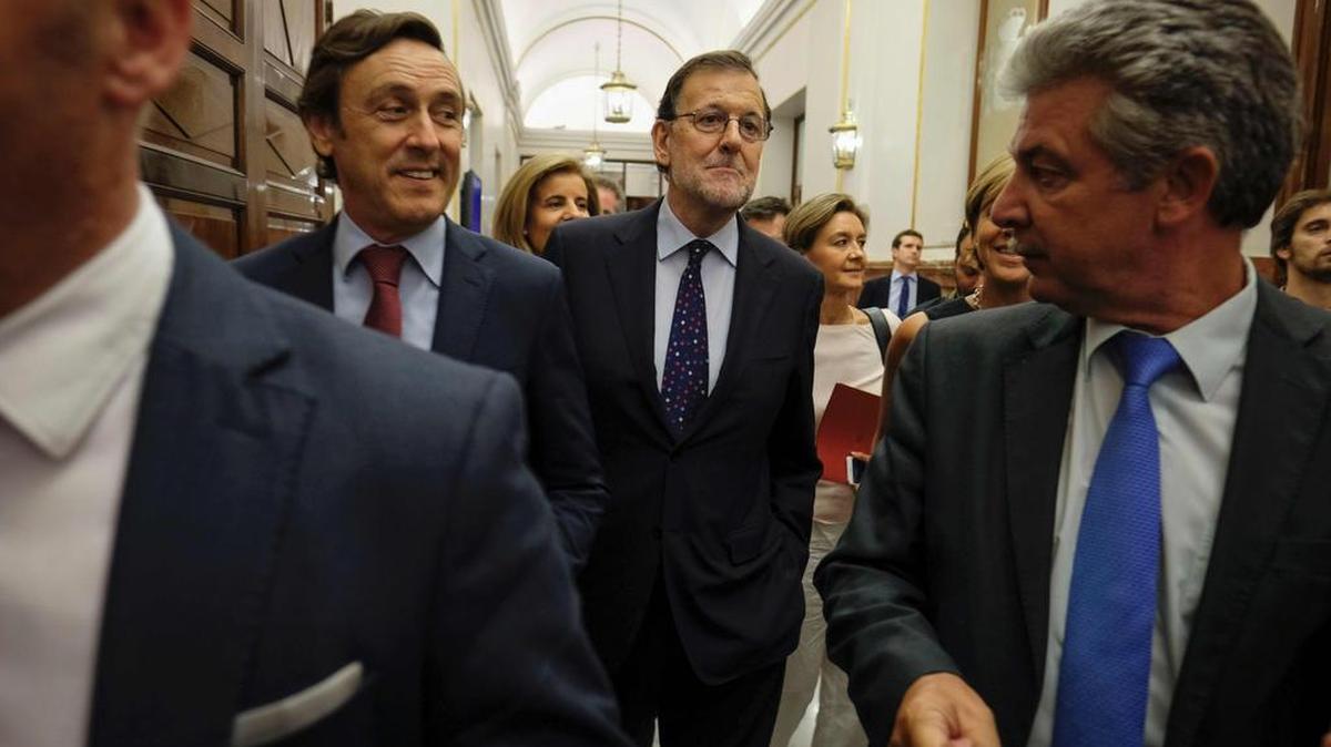 El líder interino del gobierno español, Mariano Rajoy, al centro, sale de las Cortes luego de la votación por la investidura.