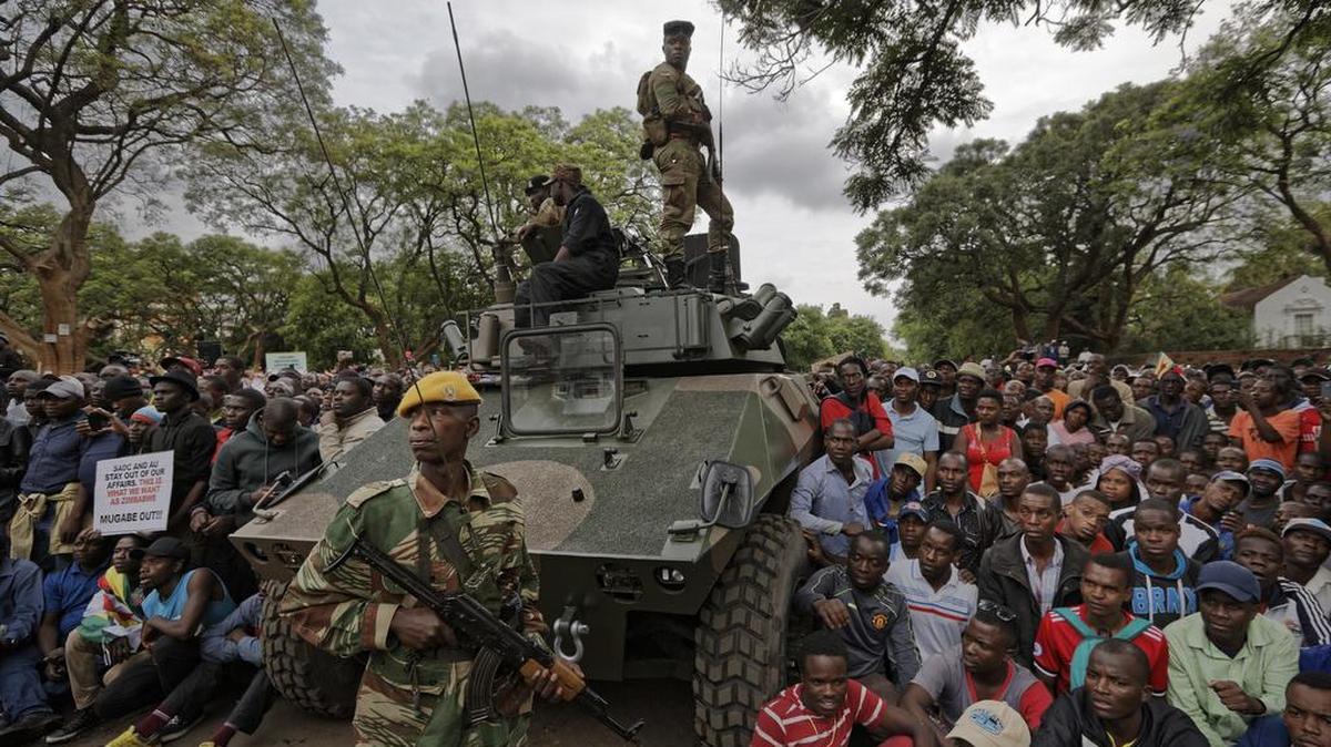 Soldados del ejército montan guardia mientras una multitud que exige la renuncia del presidente de Zimbabwe, Robert Mugabe, se reúnen en una calle que conduce a la Casa de Gobierno en Harare.