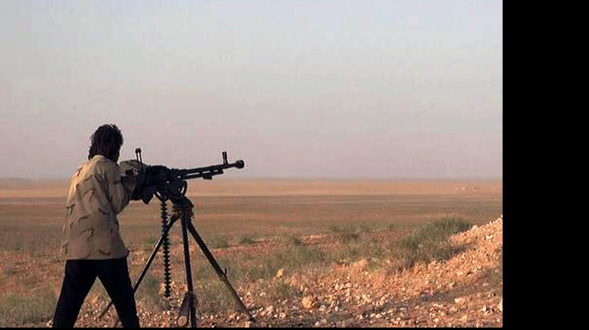 
Un militante del Estado Islámico dispara una ametralladora durante un enfrentamiento con tropas del ejército sirio, en Palmira, Siria. 

