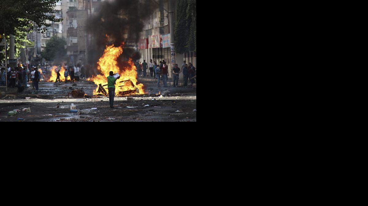 <cutline_leadin>Manifestantes mientras</cutline_leadin> se enfrentan a la policía antidisturbios durante una protesta contra el Estado Islámico (EI) en Diyarbakir, en el sureste de Turquía.