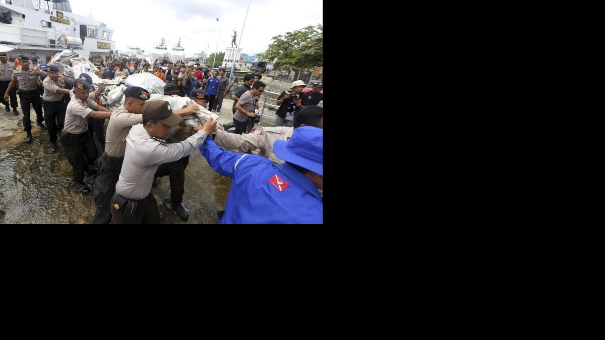 <cutline_leadin>Policias indonesios</cutline_leadin> transportan parte del fuselaje recuperado del avión de AirAsia siniestrado a su llegada al puerto de Panglima Utar Kumai, en Borneo.<252><252>