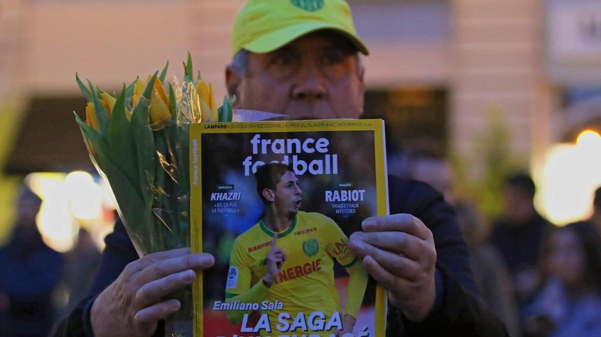 Un hombre muestra la portada de la revista France Football con la foto del futbolista argentino Emiliano Sala en la portada, durante una concentración de apoyo convocada anoche en Nantes (Francia).
