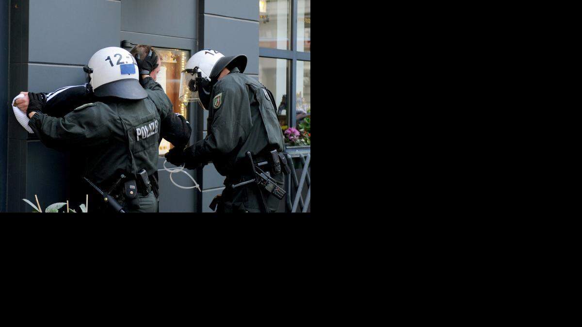 
Dos agentes alemanes detienen a uno de los manifestantes que atacó a la policía el domingo durante una violenta protesta.


