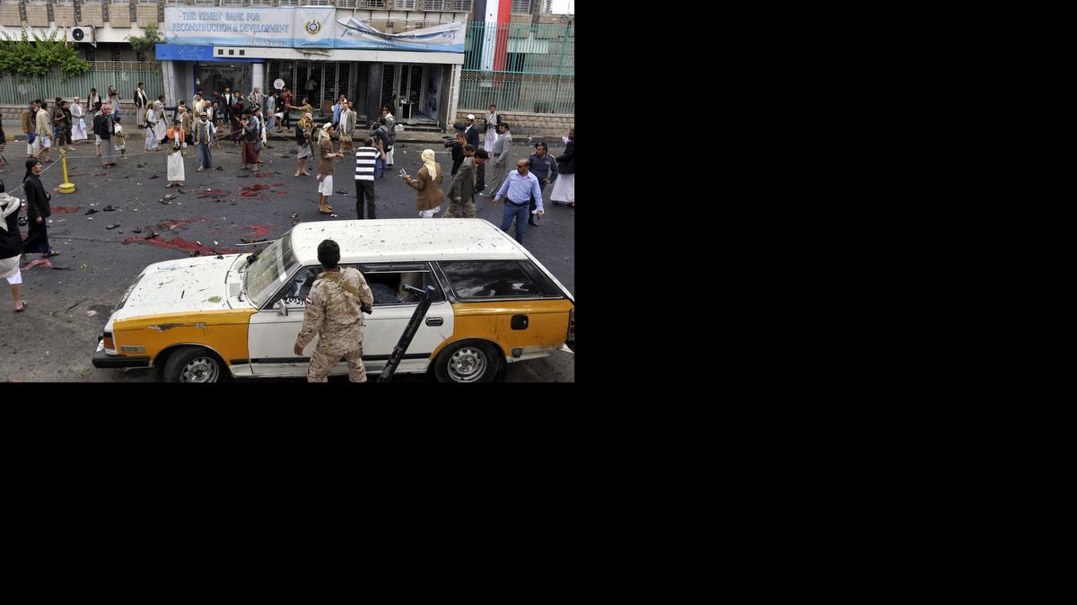 
Yemenies en el escenario del atentado suicida perpetrado contra una manifestación del movimiento rebelde chiita de los hutíes en el centro de la capital yemení, Saná, el jueves.

