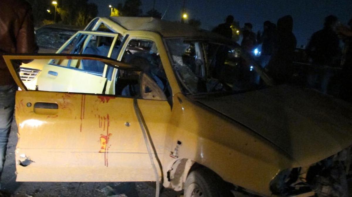 Una foto tomada el 15 de febrero de 2017 muestra a iraquíes reunidos alrededor de un vehículo dañado y manchado de sangre en el área de Habibiya, cerca del vasto distrito de Sadr City en el norte de Bagdad, después de un ataque con bomba.