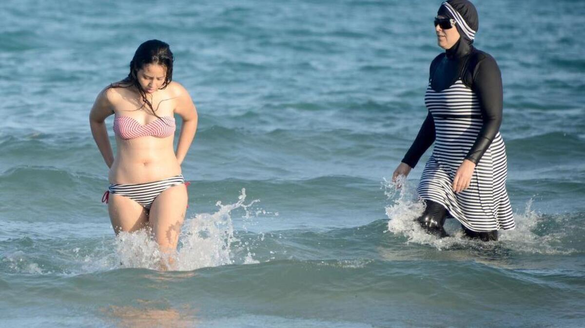Foto de archivo del 16 de agosto de 2016 muestra a dos mujeres tunecinas en la playa Ghar El Melh cerca de Bizerta, al noreste de la capital de Túnez. Una lleva un "burkini", un traje de baño de cuerpo completo diseñado para las mujeres musulmanas.