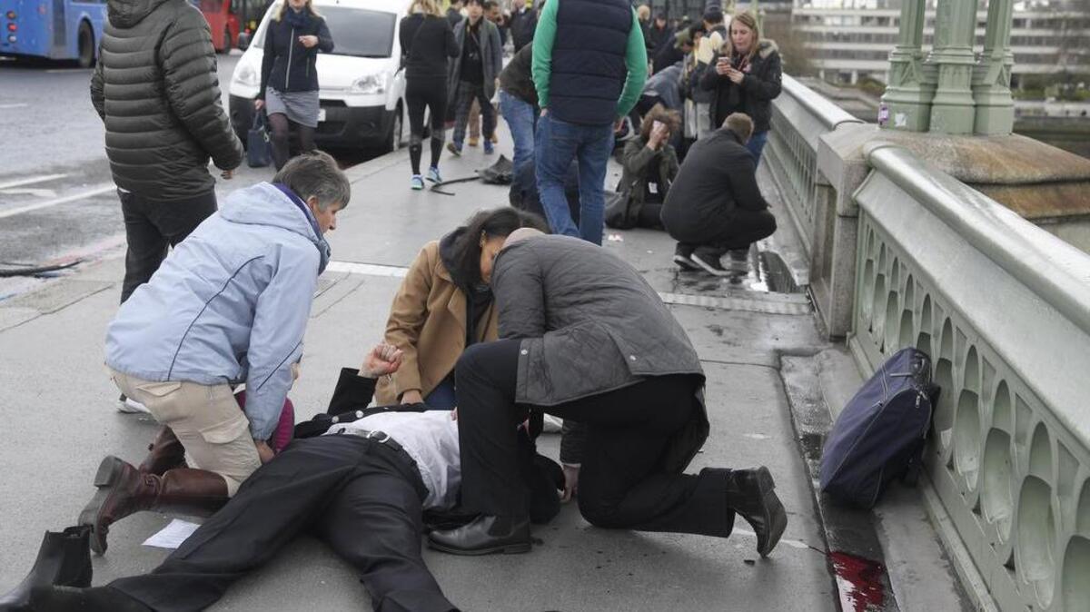 Una persona herida por el ataque terrorista del miércoles en el ataque recibe asistencia de los transeúntes en el Puente de Westminster en Londres.