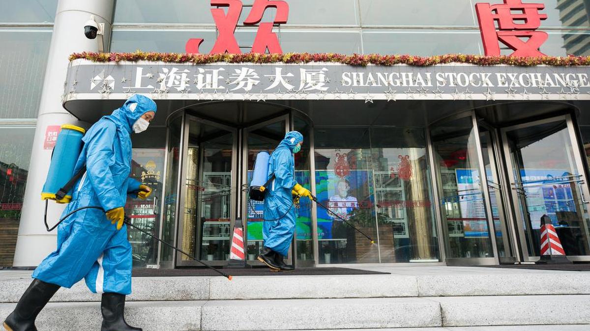 Empleados médicos fumigan el lunes frente al edificio de la Bolsa de Valores de Shanghai, China.
