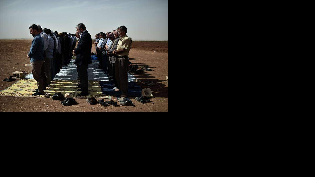 
Kurdos sirios y turcos rezan durante la oración del viernes en la frontera turco-siria frente a la ciudad siria de Ain al-Arab, conocida como Kobane por los kurdos, en las afueras de Suruc.



