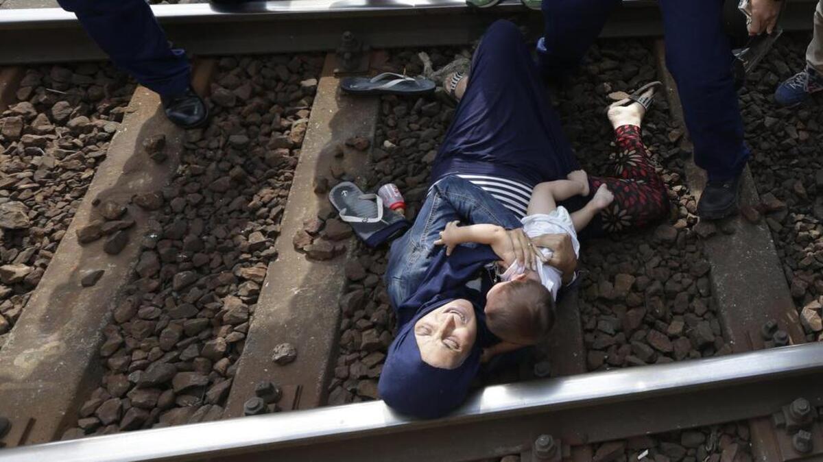 
Aferrada a su pequeño hijo, esta mujer, que busca refugio en Europa, se ha lanzado a la vía férrea en Bicske, Hungría, y se niega a que la lleven a un campo de refugiados.


