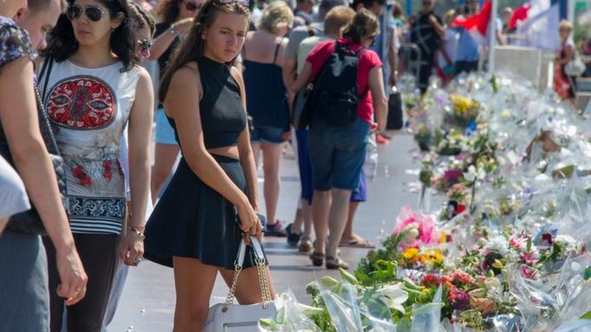 Multitud de personas se detienen ante las flores y velas depositadas en el paseo de los Ingleses en recuerdo a las víctimas, varios días después del atentado de Niza que dejó 84 víctimas mortales y más de 300 heridos.