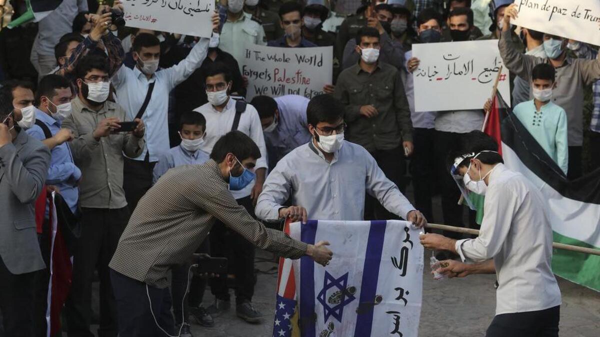 Un grupo de manifestantes se prepara el sábado para quemar representaciones de las banderas de Estados Unidos e Israel frente a la embajada de los Emiratos Árabes Unidos en Teherán.