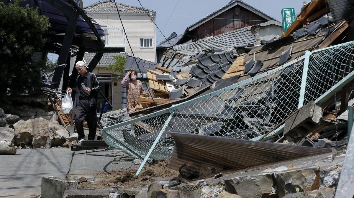 Residentes caminan entre los escombros de un edificio hoy, viernes 15 de abril de 2016, en Mashiki (Japón). La más alta intensidad del sismo, de 6.2 en la escala de Richter, se registró en Mashiki (Japón).