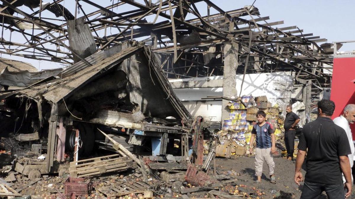 
Varias personas caminan por el lugar donde se ha producido un atentado en un mercado en Bagdad, Irak, el jueves. El grupo terrorista Estado Islámico asumió la autoría del atentado.
