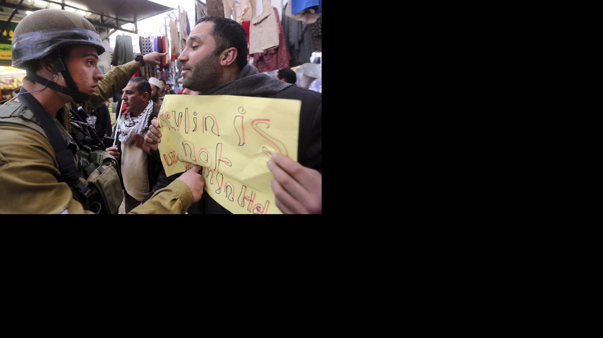 
Un manifestante palestinos (der.) pide el fin de la ocupación israelí y de los asentamientos judíos delante de un soldado israelí durante la visita del presidente israelí, Reuven Rivlin, al asentamiento judío de Beit Hadassah, en la ciudad cisjordana de Hebrón.


