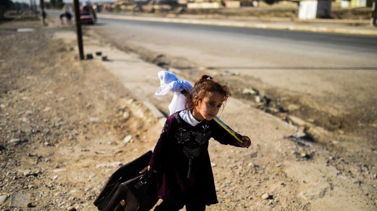Una niña iraquí lleva sus pertenencias en la aldea de Gogjali, en el extremo oriental de Mosul, el 4 de noviembre de 2016, cuando las familias huyen de la violencia debido a la operación en curso por las fuerzas iraquíes para tomar la ciudad de los jihadistas del grupo islámico.
