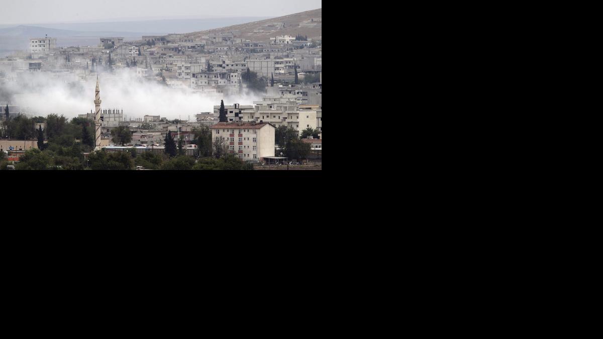 
Una columna de humo se eleva entre los edificios mientras continúa el enfrentamiento entre milicias kurdo sirias y militantes del Estado Islámico en Kobane, Siria, el viernes.


