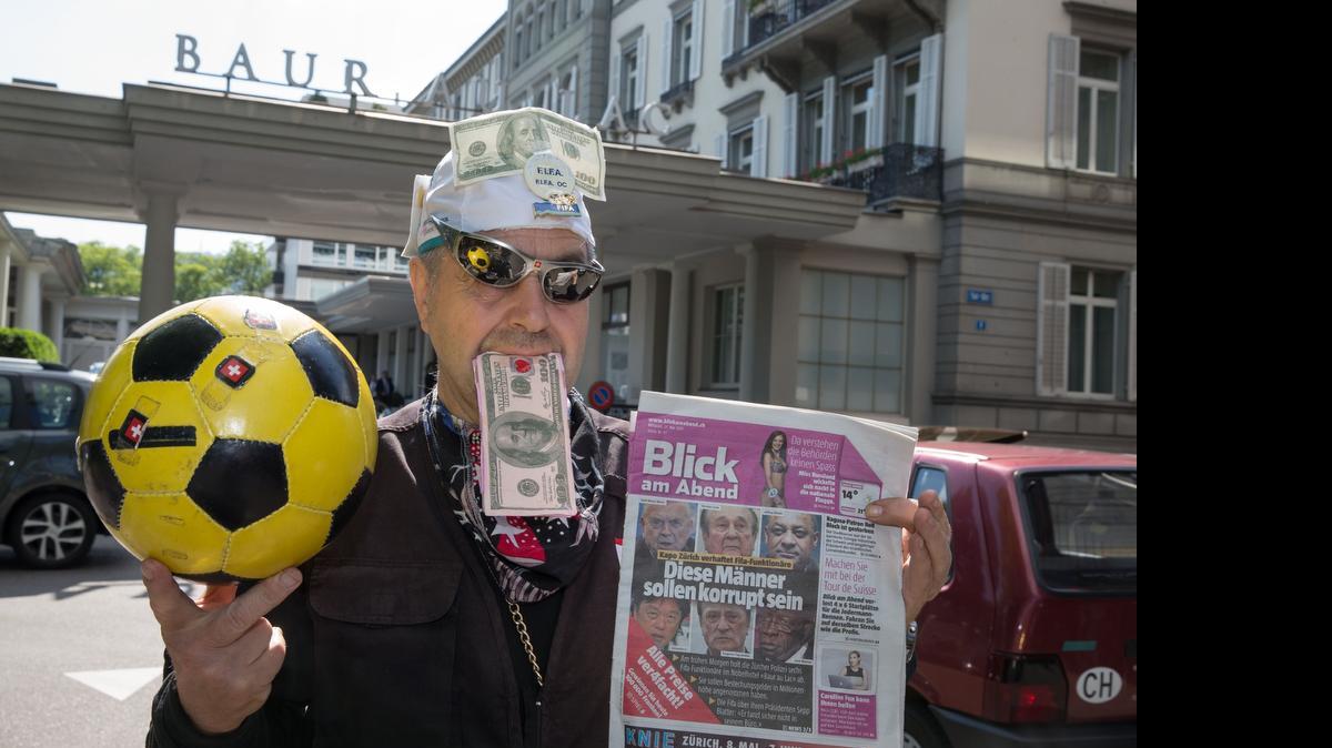 
Un hombre se burla del escándalo de corrupción afectando la FIFA, afuera del hotel Baur au Lac Zurich en Zúrick, Suiza, donde se celebrará el congreso del organismo de fútbol.

