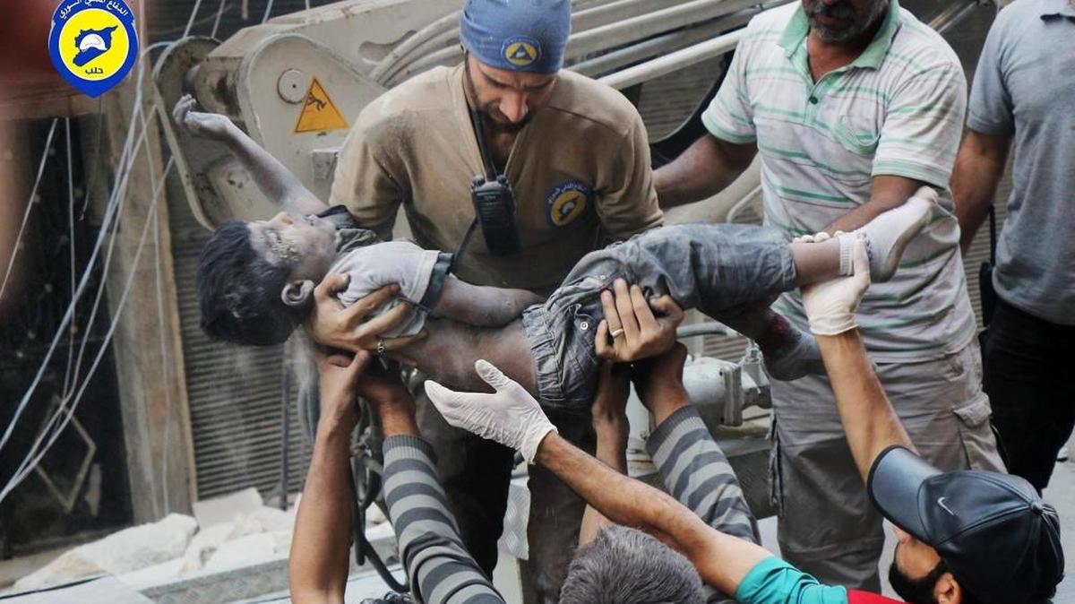 Personal de rescate en Siria saca el cuerpo de un niño de abajo de los escombros tras un bombardeo.