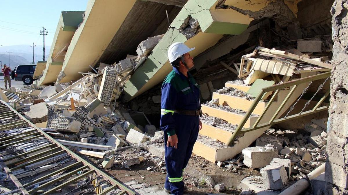 Un bombero inspecciona los restos de un edificio dañado tras el terremoto de 7,3 grados en la escala Richter registrado anoche en la frontera entre Irán e Irak, en Darbandikhan, cerca de la ciudad de Solimania (Irak) hoy 13 de noviembre de 2017.