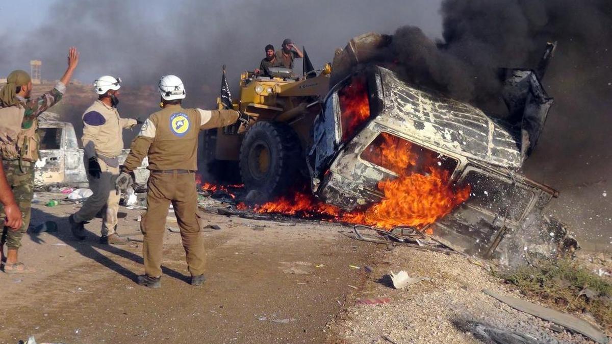 Rescatistas utilizan una excavadora para remover una camioneta destruida por ataques aéreos en Hama.