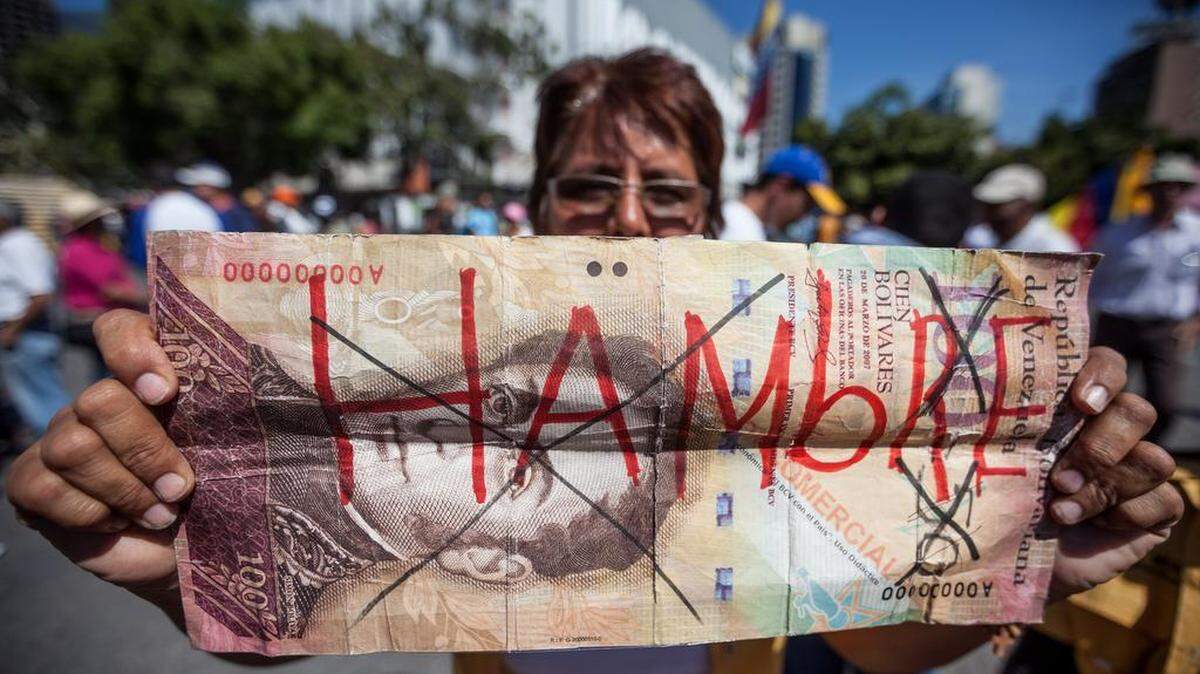 Una mujer sostiene un billete falso con la palabar "hambre" durante una manifestación antigubernamental este sábado 23 de enero de 2016, en la ciudad de Caracas (Venezuela).