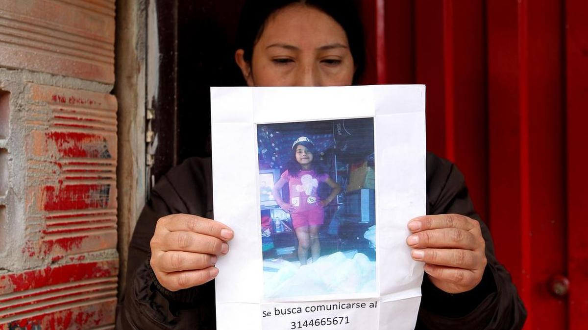 Una mujer sostiene un papel con la fotografía de la niña Yuliana Andrea Samboni Muñoz estemartes 5 de diciembre de 2016, en Bogotá (Colombia). Yuliana de 7 años fue raptada en el barrio Bosque Calderón el domingo 4 de diciembre. Las autoridades de Colombia aunaron esfuerzos para investigar el rapto, la muerte violenta y el abuso sexual de una niña de siete años cuyo cadáver fue hallado en un exclusivo apartamento de Bogotá.