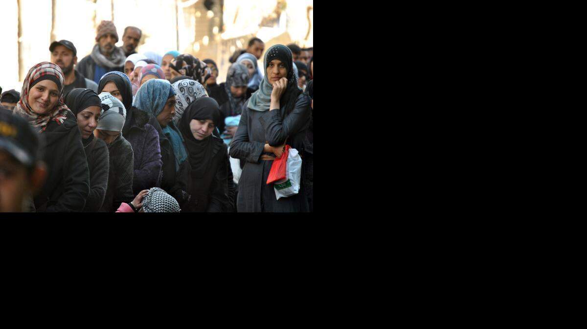 
Mujeres esperan en fila para recibir comida en el campo de refugiados de Yarmuk, en Damasco, Siria. Este campo da refugio a 18,000 palestinos. 
