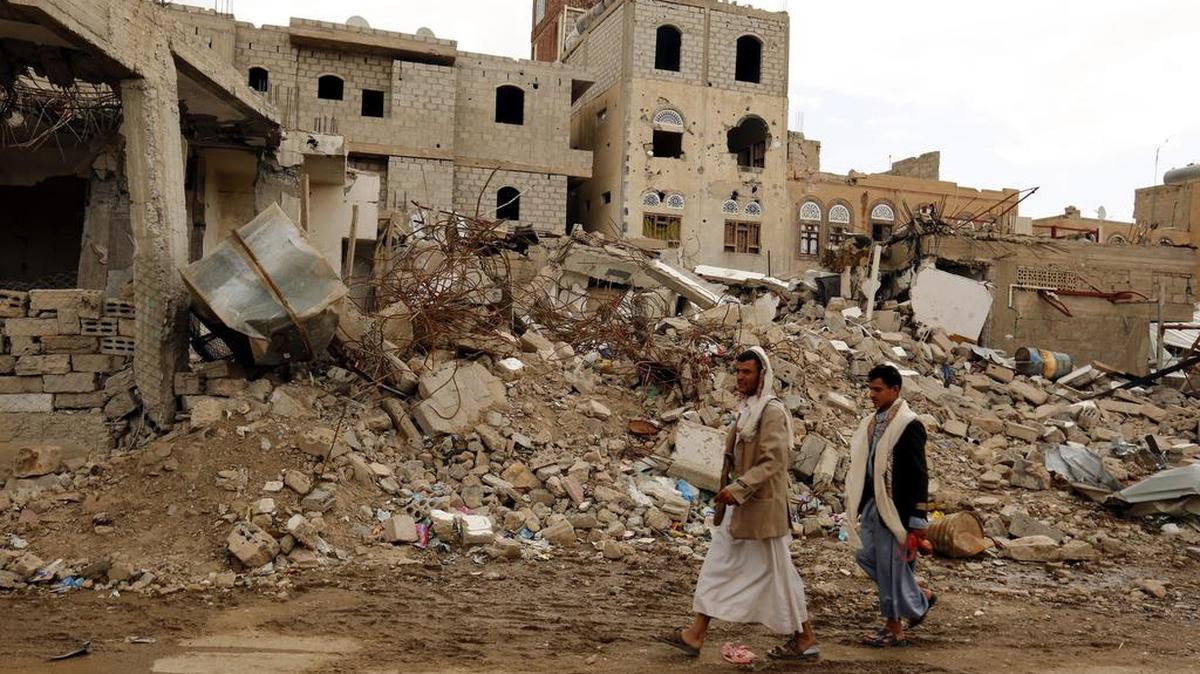 Dos hombres pasan el miércoles por delante de las ruinas de un edificio destruido por un bombardeo de la coalición árabe liderada por Arabia Saudita en Saná, Yemen.