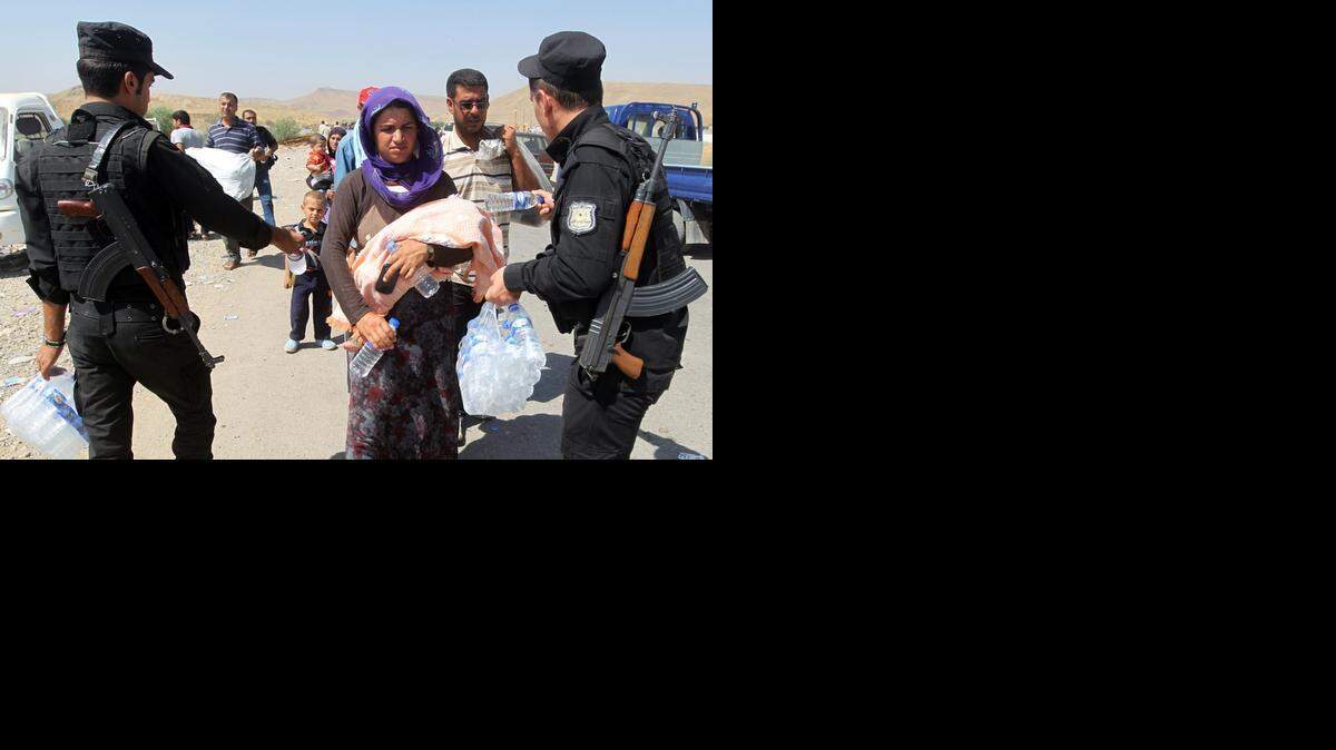 
Soldados reparten agua entre los refugiados iraquíes en la frontera con Siria.


