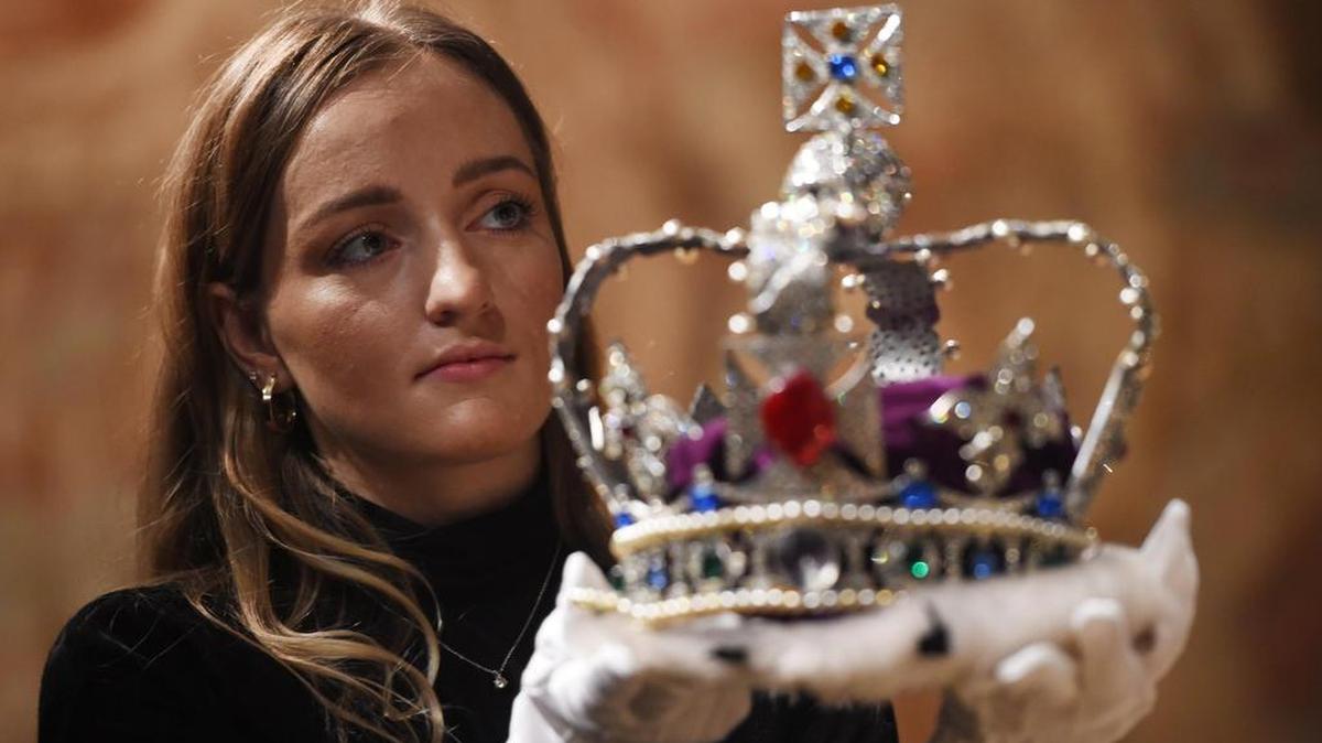 Una empleada muestra una colección de réplicas de joyas de la Corona británica fabricada en honor a la condecoración de la reina Isabel II de Inlaterra el 2 de junio de 1959, que forma parte de un lote que saldrá a subasta el próximo 15 de enero dentro de la categoría de objetos de la nobleza y la realeza de la casa de subastas británica Sotheby's, en Londres (Reino Unido), el 11 de enero de 2018.