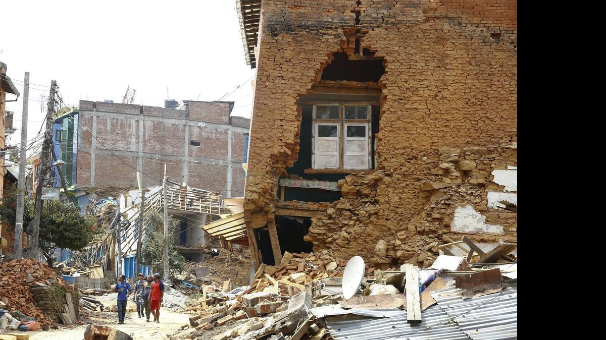 
Varios hombres caminan entre edificios destrozados, un día después del nuevo terremoto, en Chautara, Nepal, el miércoles. 
