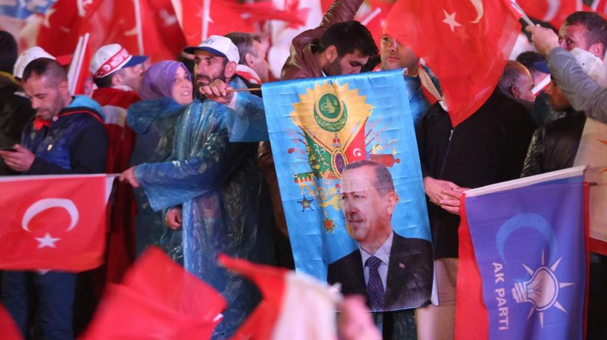Los partidarios del Partido Conservador de Justicia y Desarrollo (AKP, por sus siglas en inglés) agitan banderas turcas y un retrato del presidente turco Recep Tayyip Erdogan fuera de la sede del partido en Ankara, el 16 de abril de 2017.