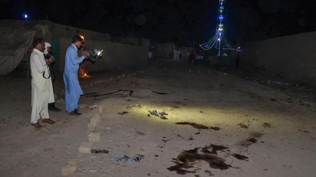 Un fotógrafo y un camarógrafo captan las manchas de sangre dejadas por un ataque suicida a las puertas de un santuario sufí en el suroeste de Pakistán.