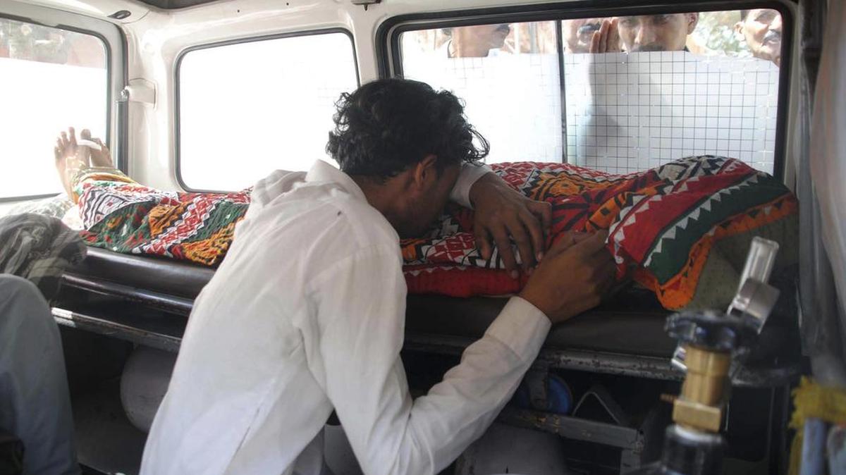 Un hombre llora junto al cadáver de su familiar, muerto por beber alcohol destilado ilegalmente, dentro de una ambulancia en Hyderabad, Pakistán, este martes.