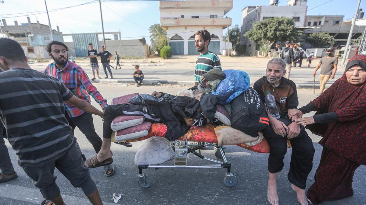 Los palestinos empujan a ancianos heridos en una cama que tomaron del hospital mientras huyen con otras familias palestinas en la ciudad de Gaza y otras partes del norte de Gaza hacia las zonas del sur en medio de batallas en curso entre Israel y el movimiento palestino Hamas.