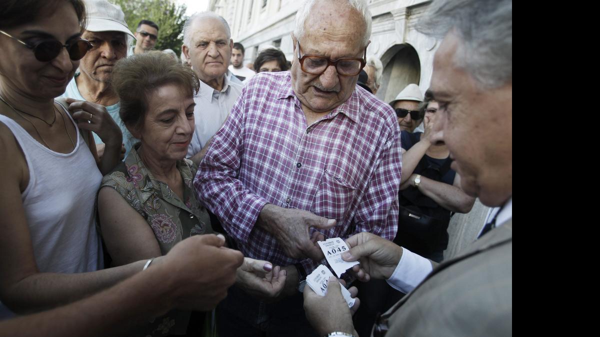 
Un empleado reparte turnos el lunes a un grupo de pensionistas frente a una sucursal del Banco Nacional de Grecia en el centro de Atenas. Los bancos de Grecia abrieron después de tres semanas de cierre.
