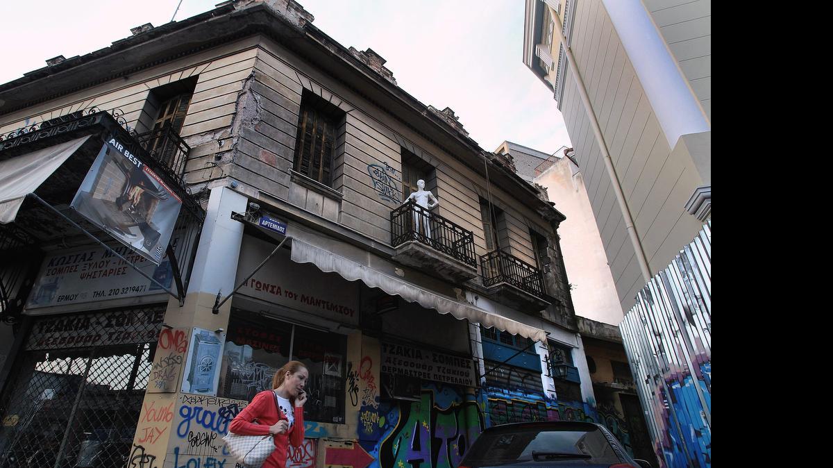 
Una mujer pasa frente a un edificio agrietado en el centro de Atenas, Grecia, país que está en intensas negociaciones con sus acreedores. 
