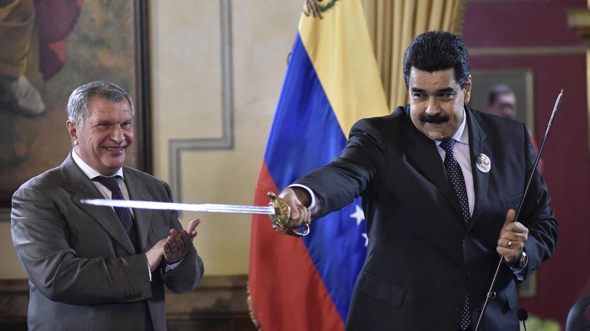 Nicolás Maduro, presidente de Venezuela, a la derecha, blande con una espada que le regaló Igor Sechin, director ejecutivo de Rosneft PJSC, después de que Eulogio del Pino, presidente de Petróleos de Venezuela SA (PDVSA) y Sechin firmaran un acuerdo con Repsol para incrementar la producción de petróleo.