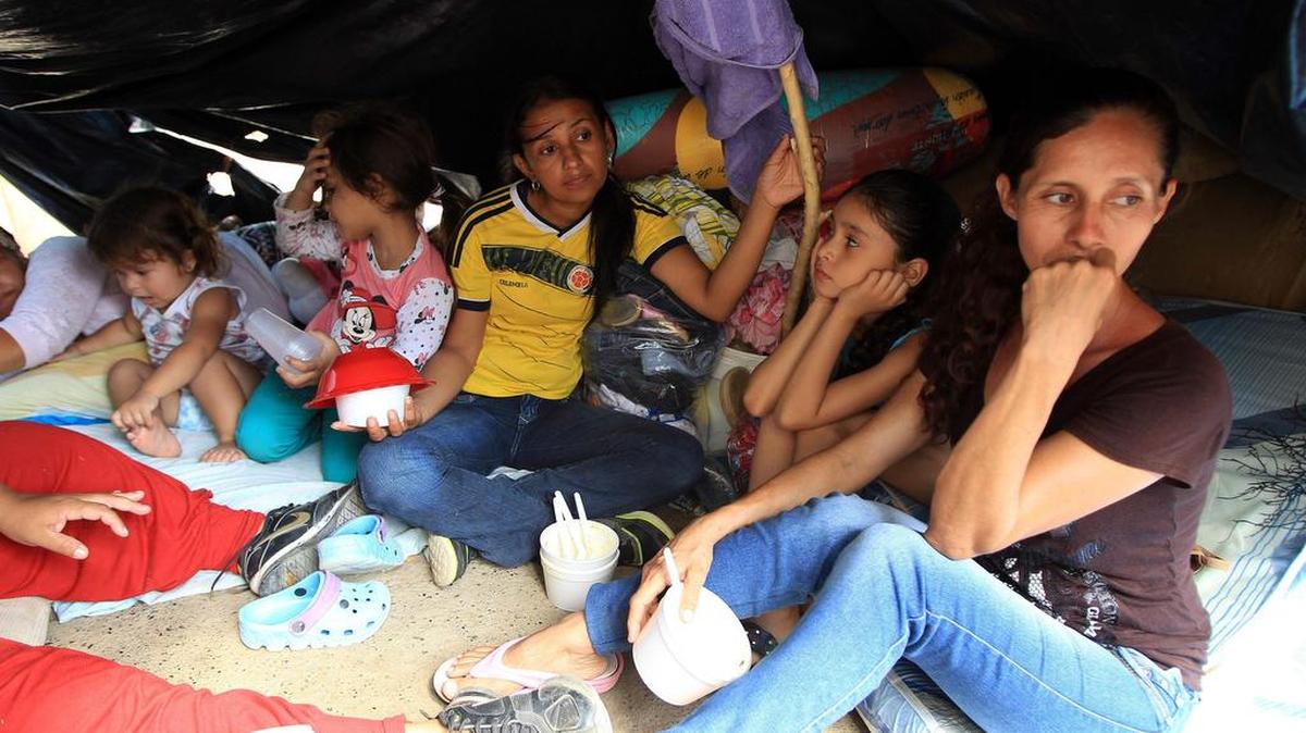 
Colombianos que han retornado voluntariamente desde Venezuela permanecen con sus pocas pertenencias bajo un plástico, en la Playa, sector de La Parada (Colombia), frontera con Venezuela.  
