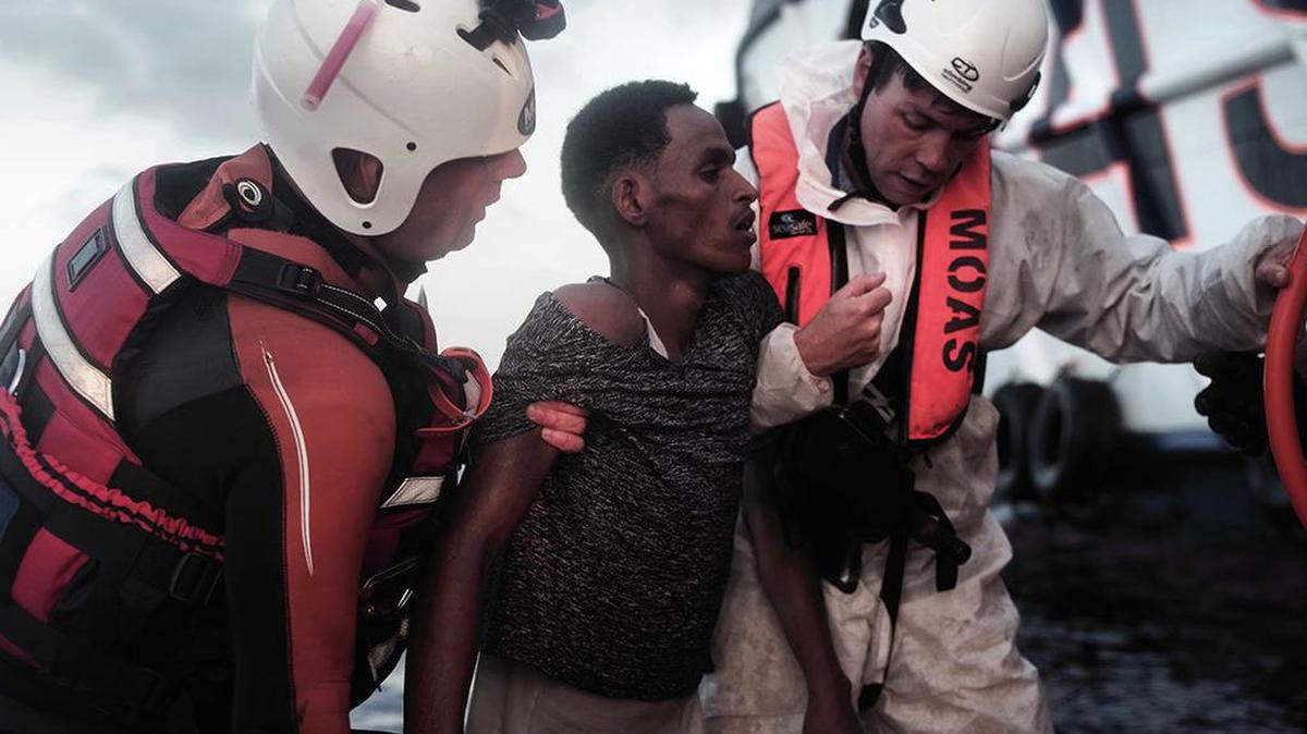 Rescatistas de la Cruz Roja italiana auxilian a un migrante casi desfallecido que fue rescatado de las aguas del Mediterráneo.