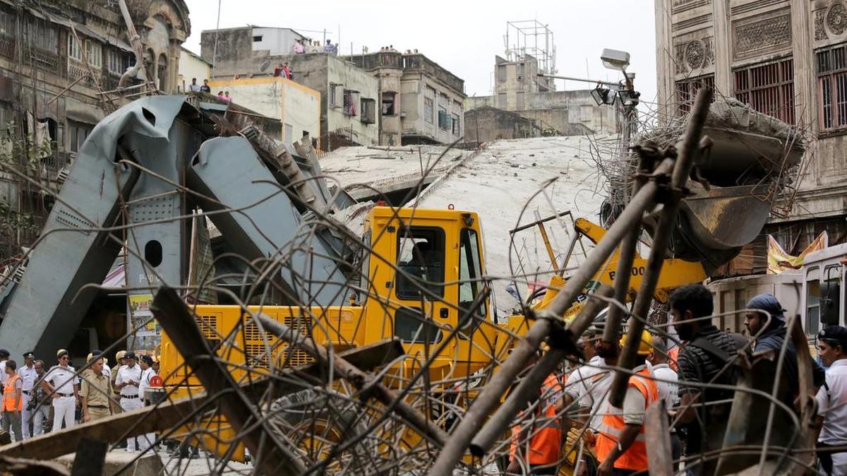 Efectivos de los servicios de rescate y personal del ejército indio trabajan en la búsqueda de supervivientes que permanecen atrapados bajo los escombros del puente que se derrumbó en Calcuta, India.