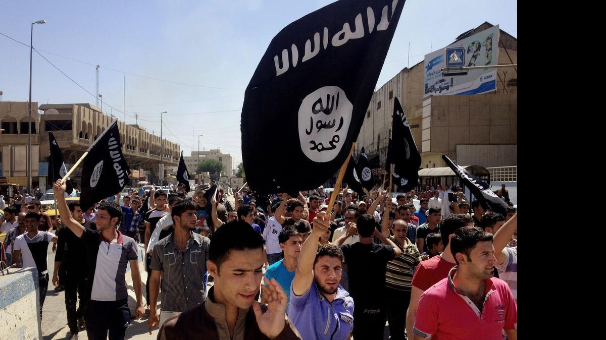 
Manifestantes en apoyo al Estado Islámico marchan frente a la sede del gobierno en Mosul, Irak.
