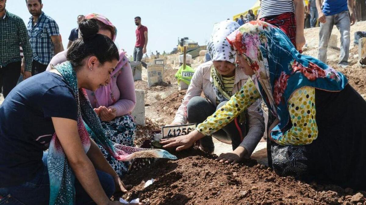 Mujeres se arrodillan junto a una tumba, durante el funeral por las víctimas del ataque suicida en una fiesta de boda, que dejó decenas de fallecidos en Gaziantep, Turquía.
