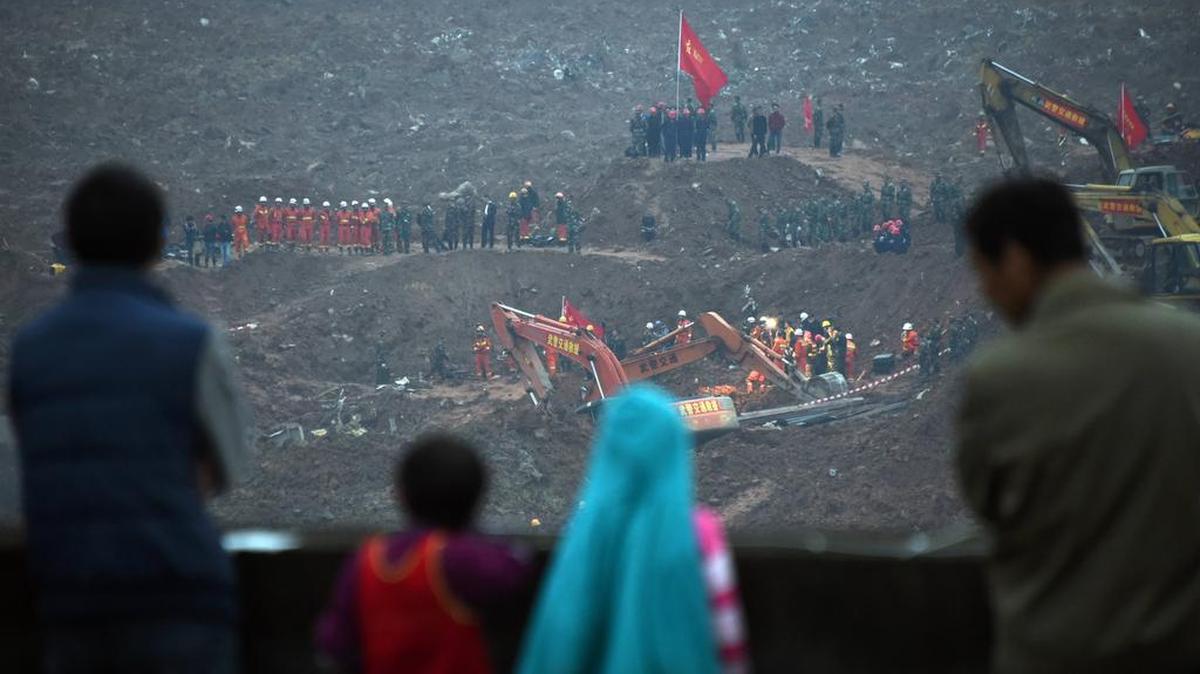 Varias personas observan este lunes mientras los rescatistas buscan sobrevivientes de un enorme deslizamiento de tierra en Shenzhen, China.