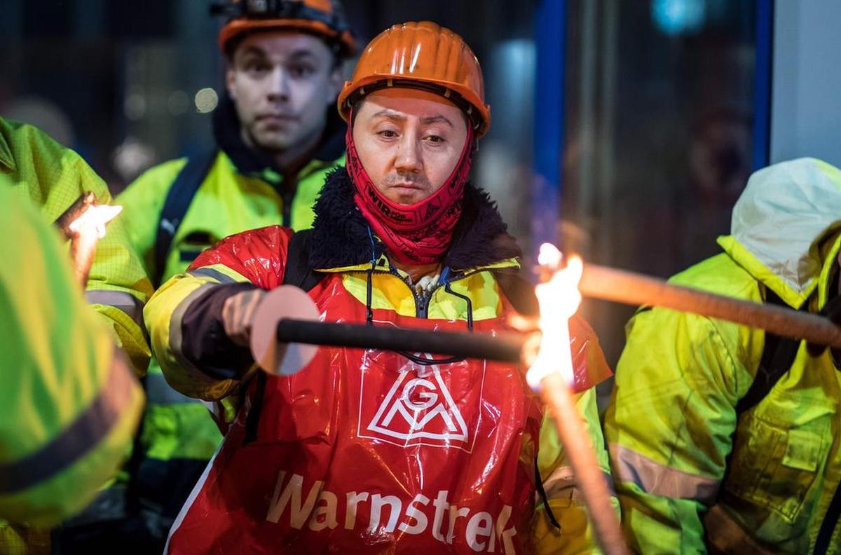 Un empleado de la empresa Aluminium Norf GmbH enciende una antorcha mientras él y sus colegas realizan una advertencia el 9 de enero de 2018 en Neuss, en el oeste de Alemania.
