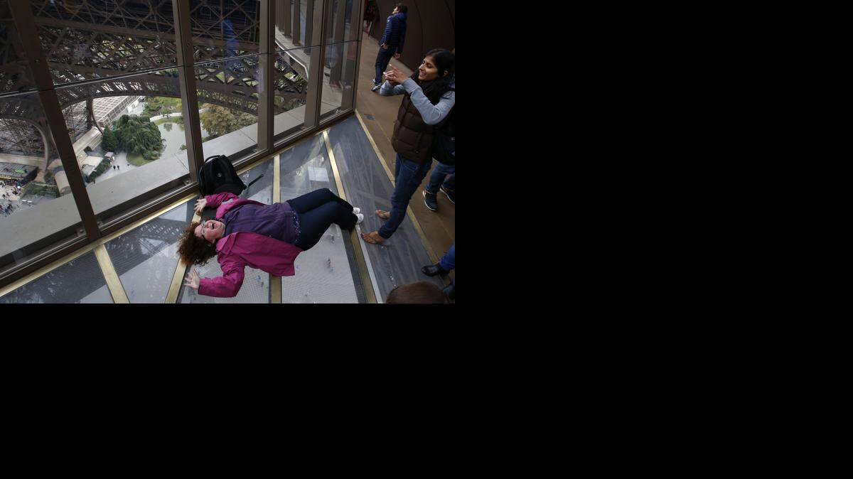 
Una visitante se toma una foto a una mujer acostada sobre el nuevo piso de vidrio en la Torre Eiffel durante la inauguración este lunes en la capital francesa.


