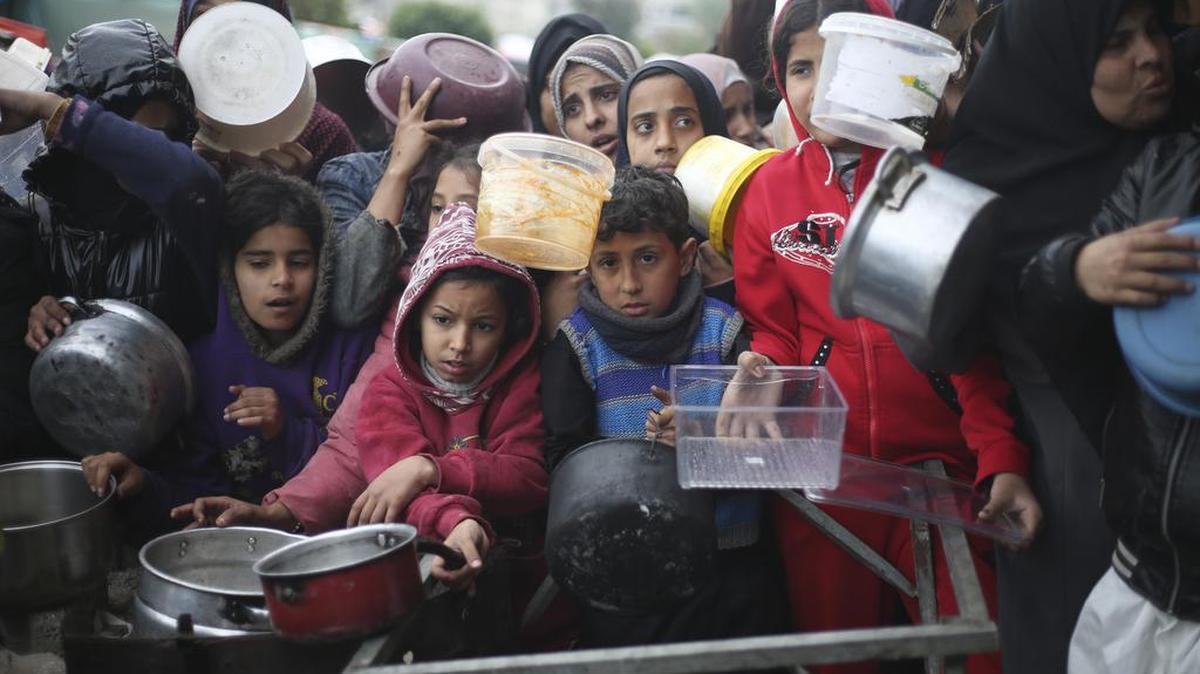 Los palestinos hacen fila para la distribución gratuita de alimentos durante la actual ofensiva aérea y terrestre israelí en Khan Younis, Franja de Gaza, el viernes 2 de febrero de 2024.